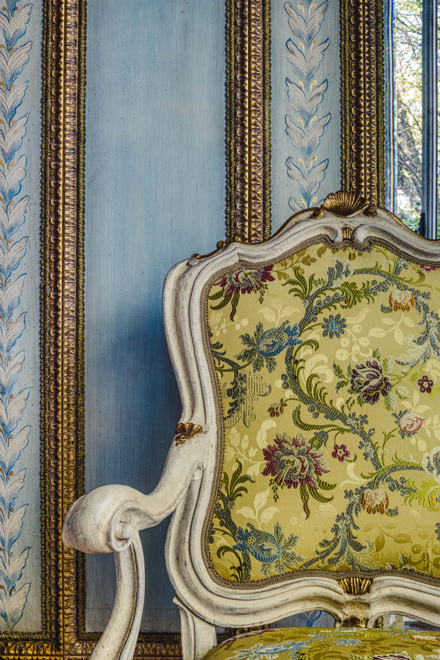 Detail of an antique green chair on a blue wood wall in the Bussandri Villa