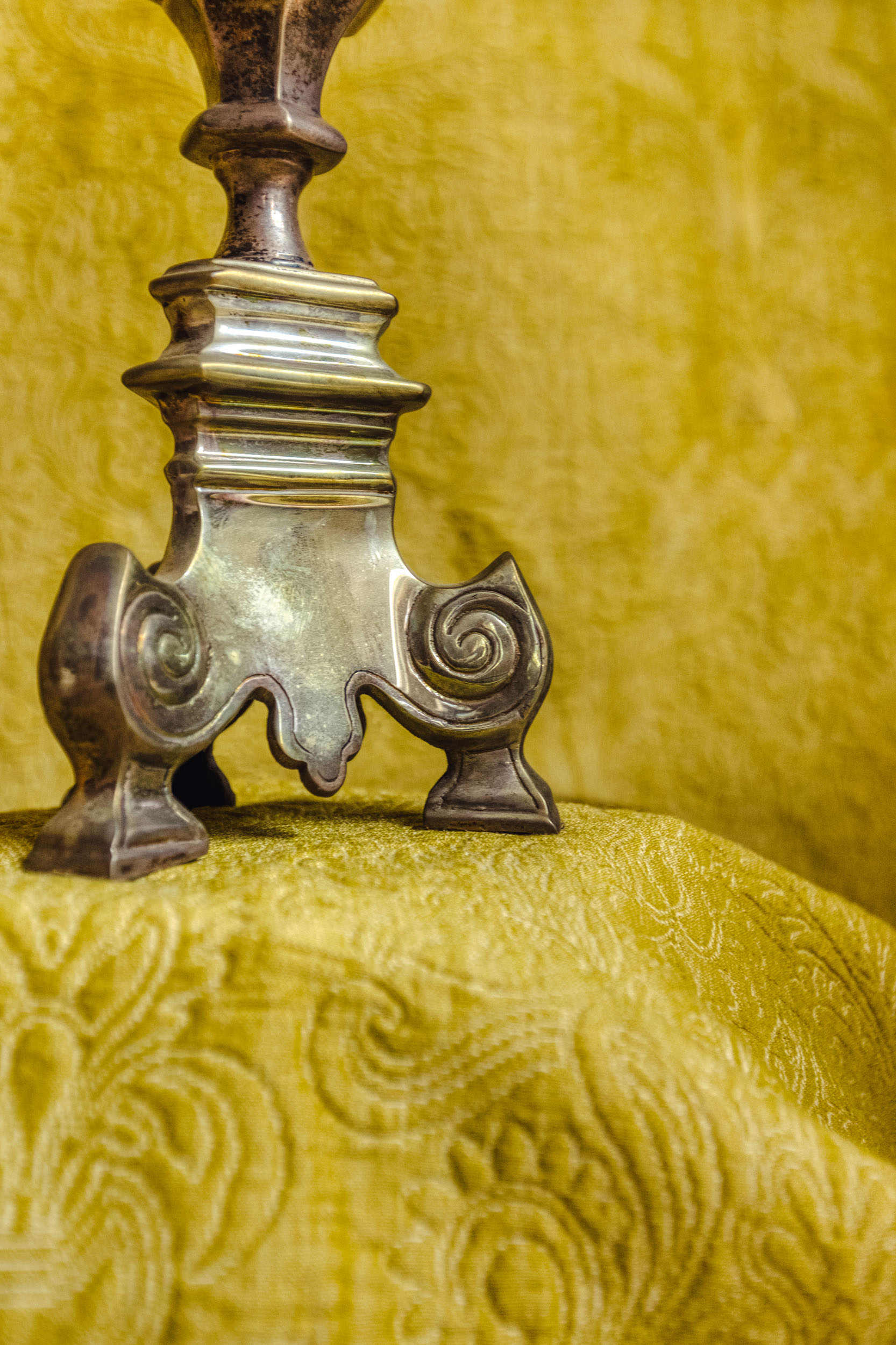 Detail of a silver lamp base on a yellow backdrop in the Bussandri Villa